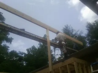 Carpenter setting a ridge beam over a new addition frame — Ice Dam Removal by Roofing Brothers in Houston