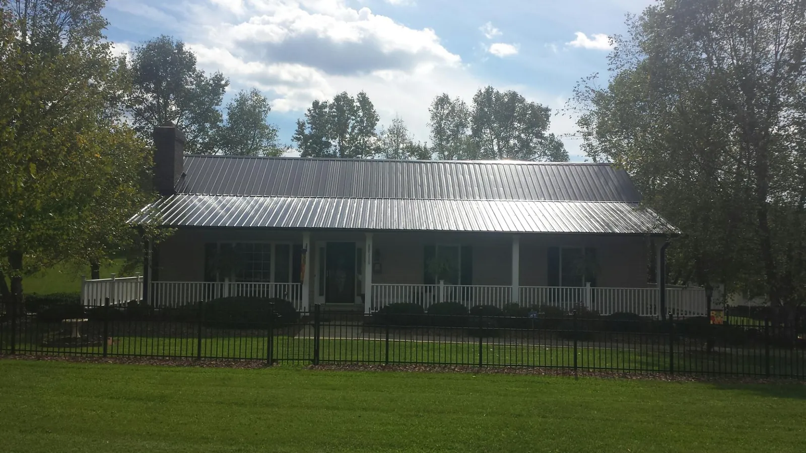 Gray metal roof on a brick ranch with a full width front porch — Gutter Guard Installation work by our crew in Houston